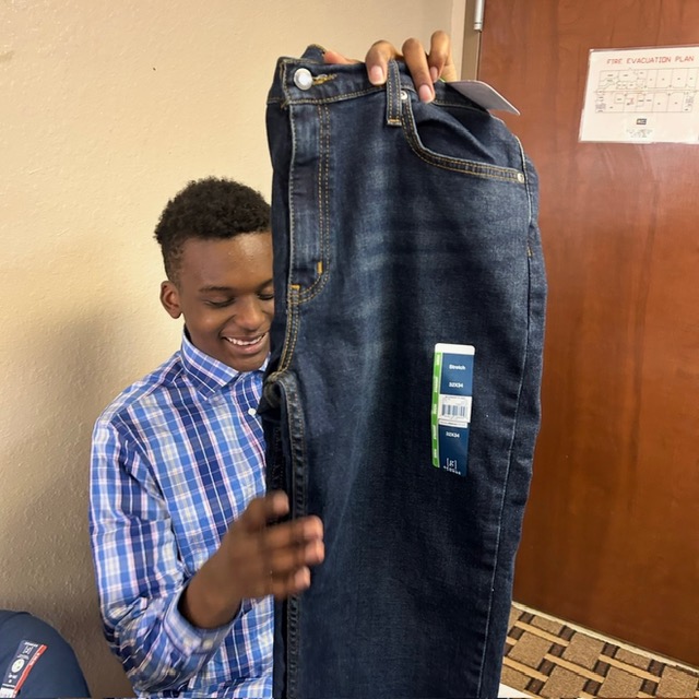 Young man holding a new pair of jeans at the Duluth, GA giveaway